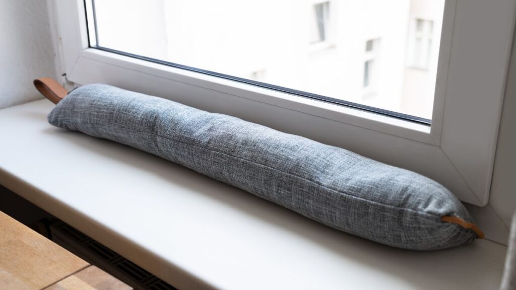 Huzat az álomban jelentése Egy szürke huzat fekszik az ablakpárkányon, a belső tér világos háttérrel.