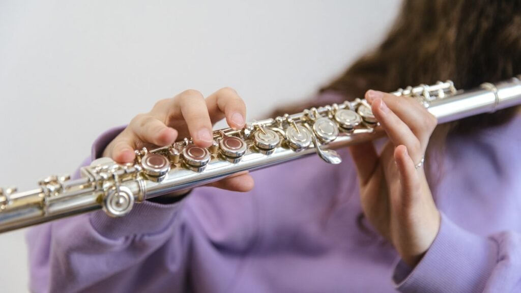 Egy kéz furulyát tart, amely az öröm és harmónia szimbóluma lehet.