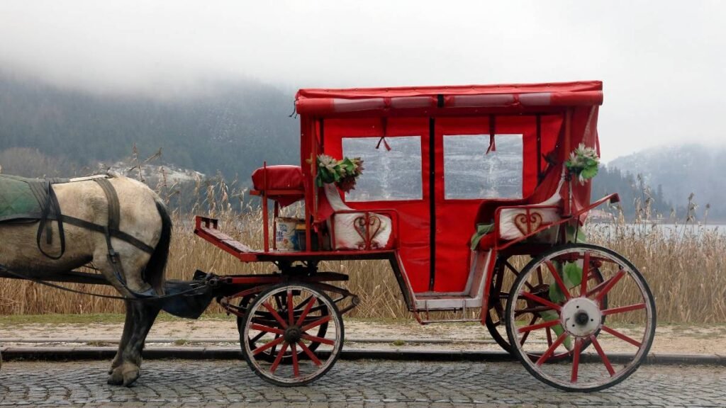 Egy piros hintó áll egy köves úton, háttérben ködös tájjal.