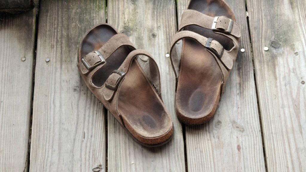 Két saru áll egy fából készült padlón, a napfényben megvilágítva.