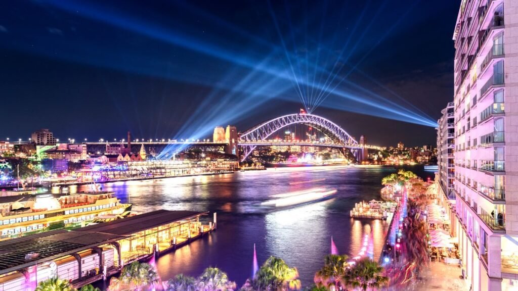 Éjszakai rakpart látképe, színes fényekkel és vízparti sétánnyal.