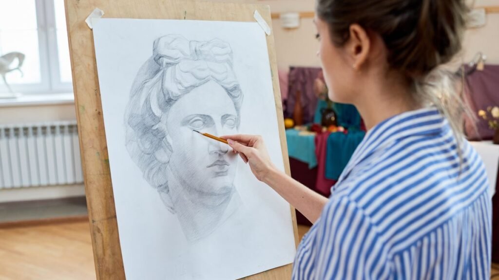 Egy nő rajzol egy klasszikus szobrot ábrázoló képet, mély koncentrációval.