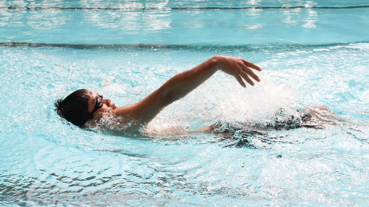 Egy fiatal fiú hátúszás közben, vízben, nyugodt környezetben.