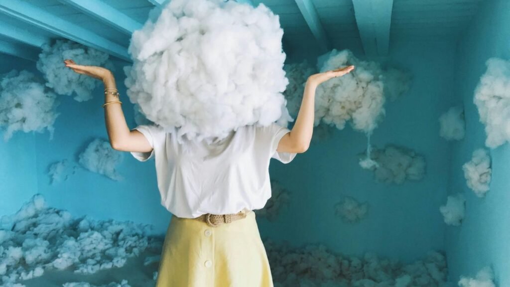 Egy nő feje felett felhő formájú anyag látható, színes háttér előtt.