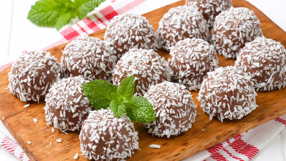 Kókuszgolyók egy fából készült tálcán, friss mentalevelekkel díszítve.