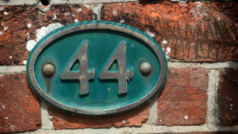44-es szám álomban mit jelent? A zöld színű, ovális táblán a 44-es szám látható, téglafalon.