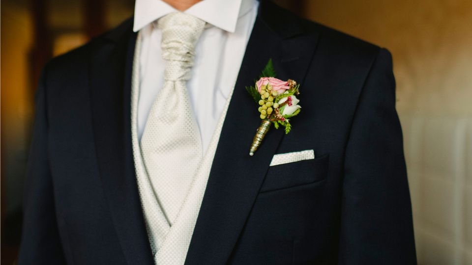 Egy elegáns vőlegény öltöny, rózsaszín virággal a hajtókán.