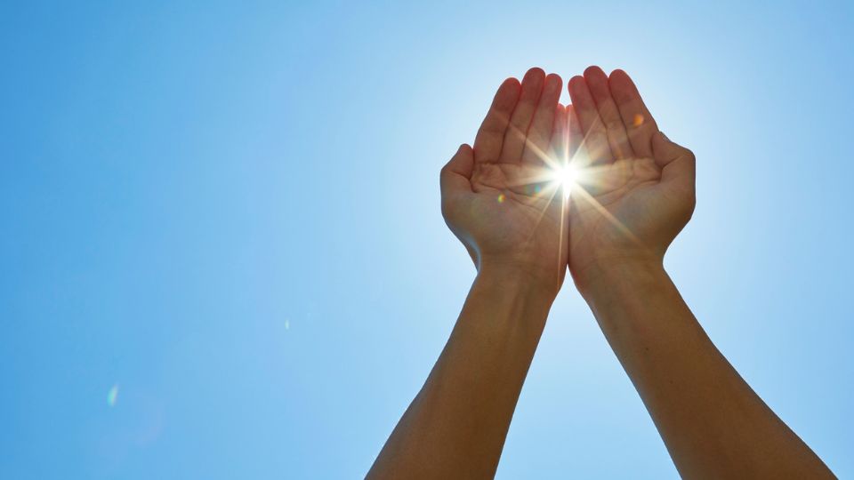 Álmokból valóság: Hogyan váltsd valóra álmaid és érd el a céljaid? Két kéz, amelyek a napfény felé nyúlnak, szimbolizálva az álmok megvalósítását.