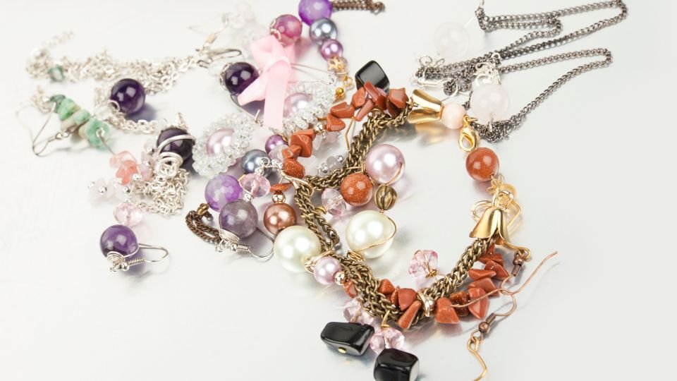 Színes bizsuk, fülbevalók és nyakláncok egy asztalon, tükrözve a kreativitást.