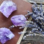 Három ametiszt kristály egy barna könyvön, levendulával körítve.
